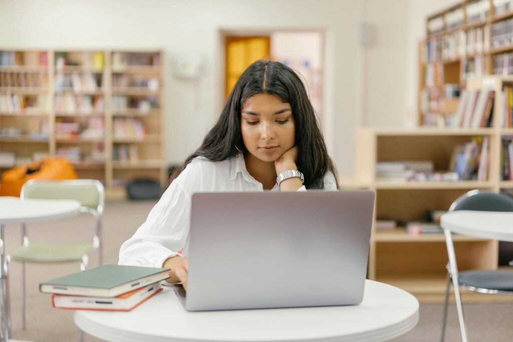 Student preparing for scholarship interview 2025 with notes and laptop.